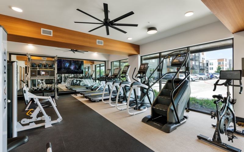 Fitness center with large windows behind cardio machines and 